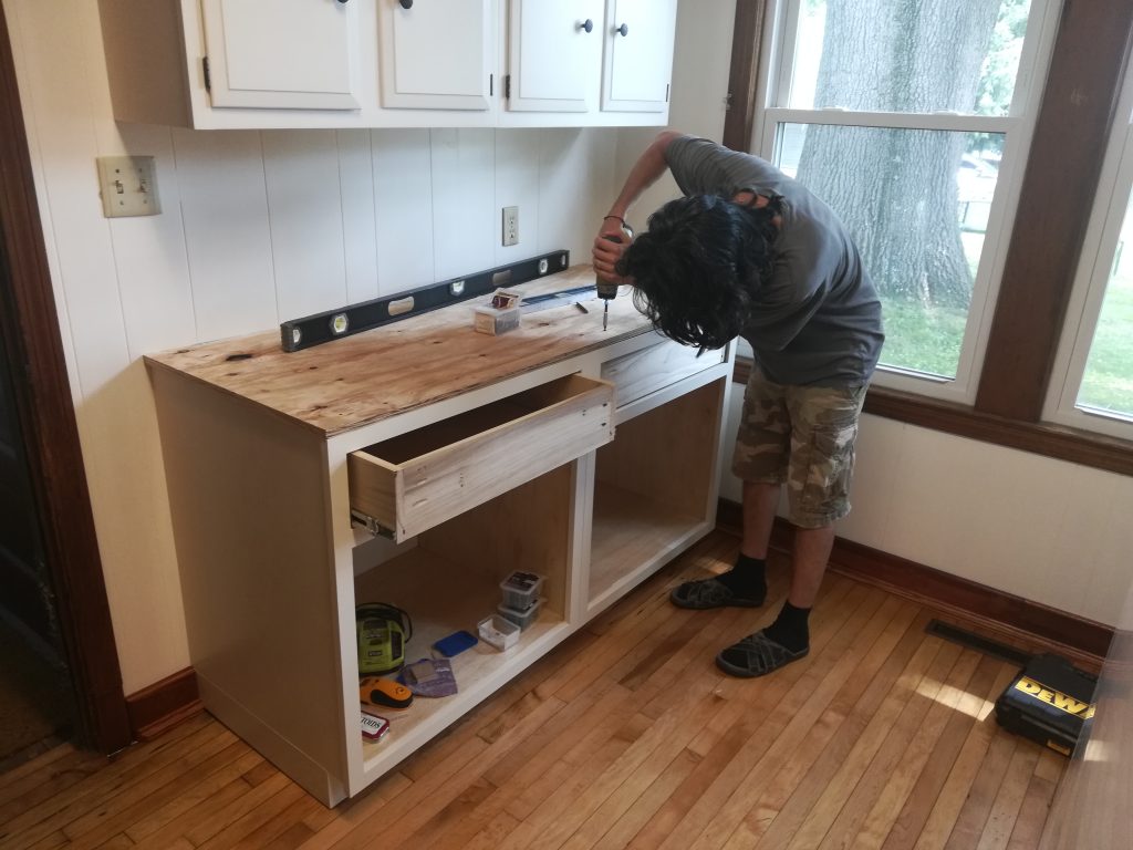 my husband screwing down the plywood as a base for tiling countertops with granite
