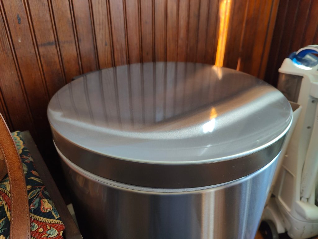 stainless steel trash can after cleaning with white green cloth