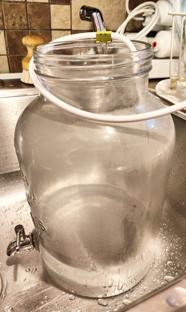 glass jug dispenser being filled with RO water